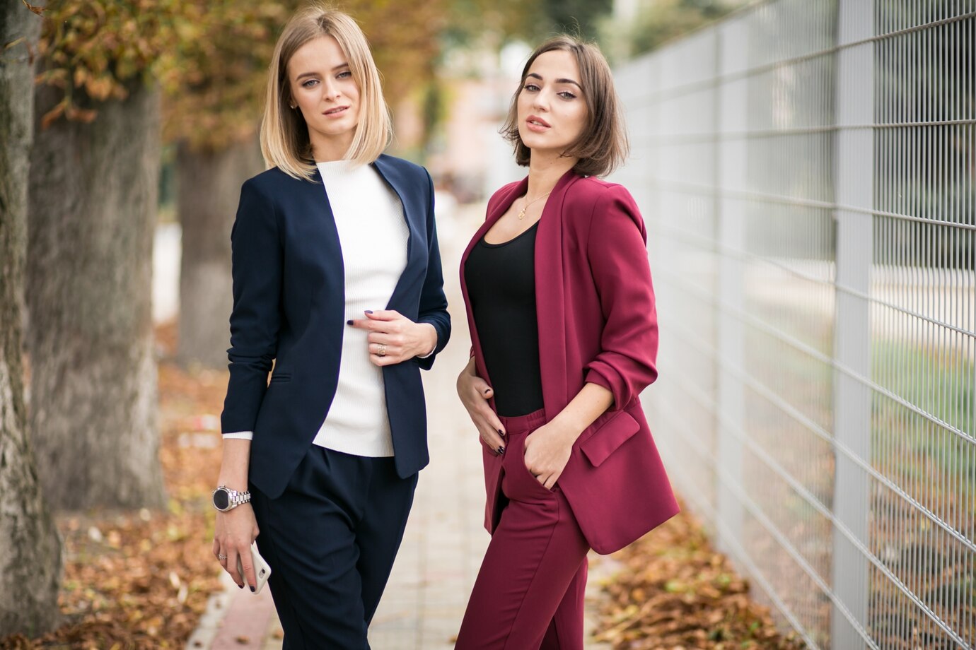 Two women in stylish blazers stand confidently 