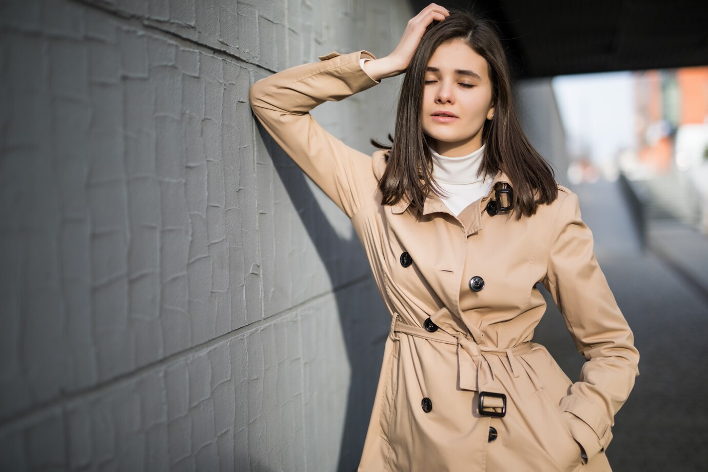 A woman poses stylishly wearing a beige trench coat