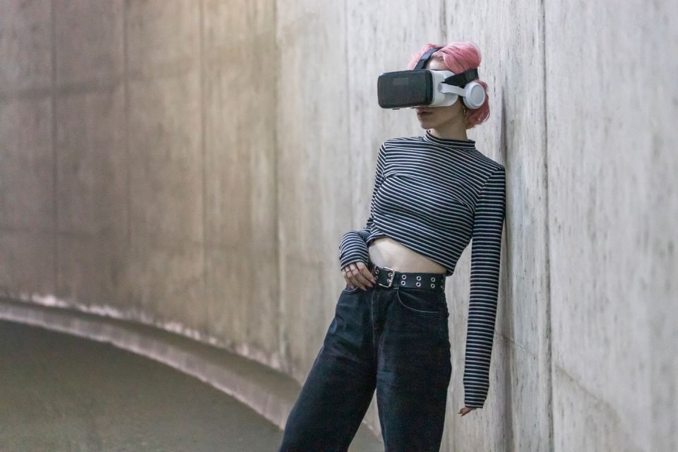 A person wearing a VR headset and headphones and dressed in a striped shirt and black pants.