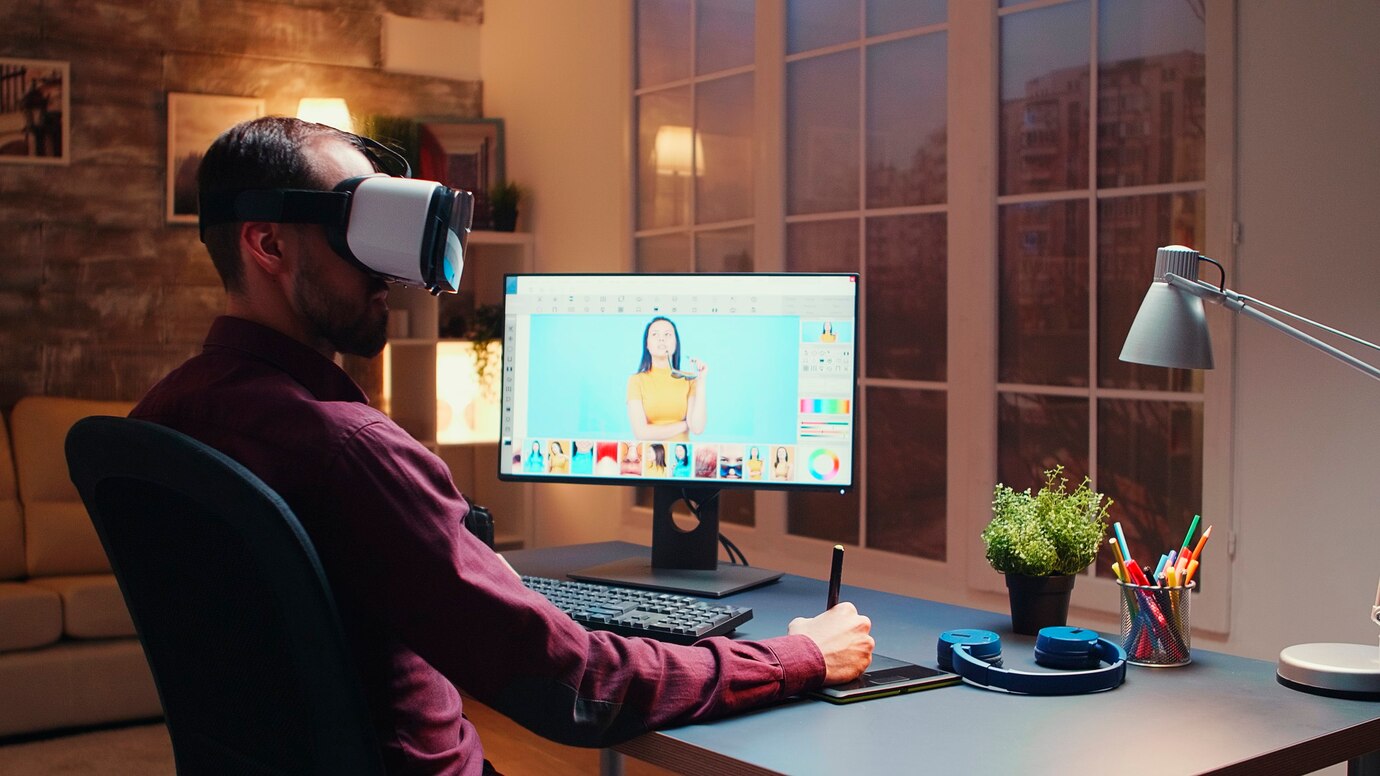  A person wearing a VR headset sits at a desk, digitally editing images on a computer screen in a cozy,