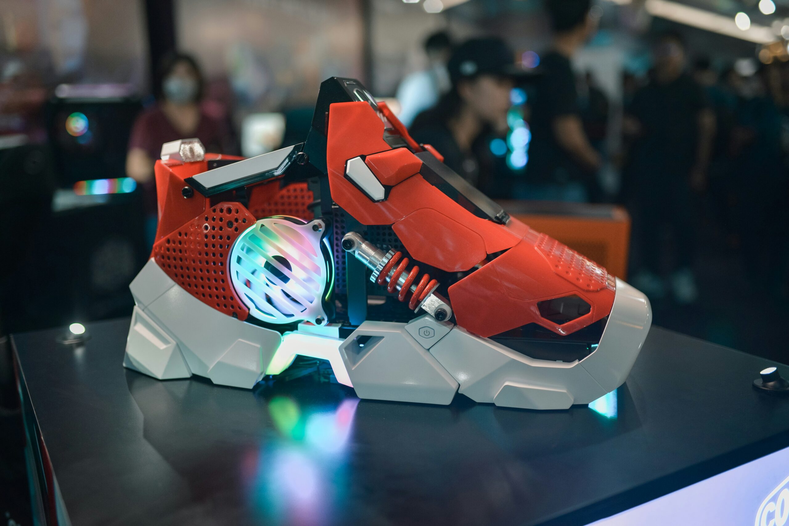 A futuristic red and white gaming console with a glowing fan and intricate design displayed a tech event.
