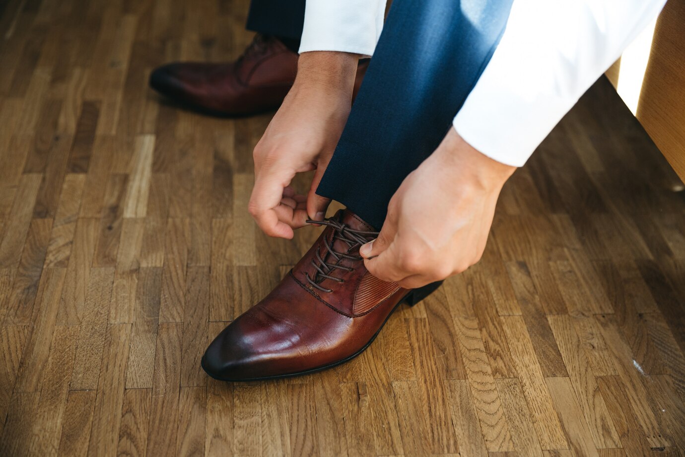 man in a white shirt and navy trousers ties the laces