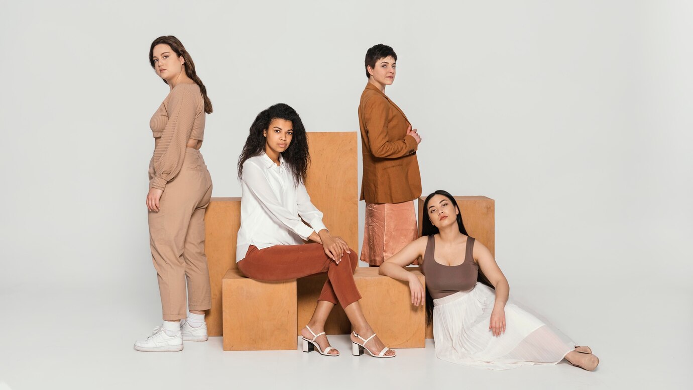 Four women in varied outfits posing with wooden blocks on a plain background.