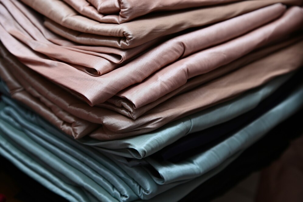Stack of neatly folded fabrics in shades of blue, gray, and pink.